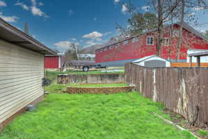 View of yard featuring a storage shed, fence, and an outdoor structure