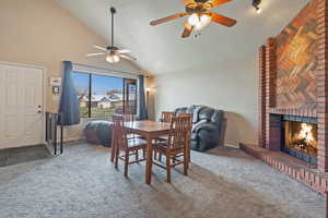 Dining area with lofted ceiling, carpet floors, a brick fireplace, and a ceiling fan