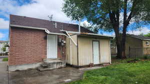 Back of property featuring a yard, roof with shingles, and fence
