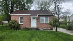 View of front of house featuring a shingled roof, a front lawn, and fence