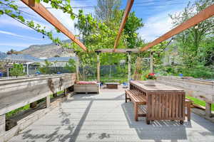 View of patio with a deck with mountain view, outdoor dining space, and fence