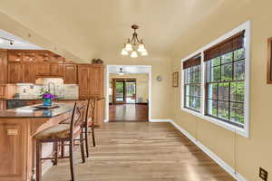 Dining area featuring ceiling fan with notable chandelier, baseboards, and light wood-style floors