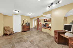 Interior space featuring a textured ceiling, baseboards, and arched walkways