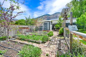 View of yard featuring a vegetable garden, an outbuilding, a shed, and a mountain view