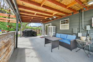 Wooden terrace featuring a grill and an outdoor living space
