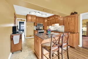 Kitchen with baseboards, a sink, dark stone countertops, tasteful backsplash, and appliances with stainless steel finishes