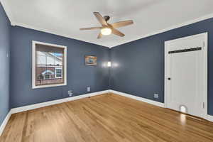 Unfurnished room featuring wood finished floors, baseboards, and ornamental molding