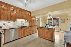 Kitchen featuring a sink, stainless steel appliances, dark stone countertops, decorative backsplash, and glass insert cabinets