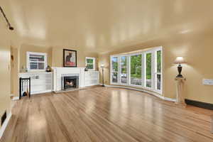 Unfurnished living room with a premium fireplace, baseboards, visible vents, and wood finished floors
