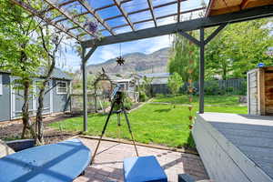 View of patio / terrace featuring an outbuilding, a deck with mountain view, a pergola, a fenced backyard, and a storage unit