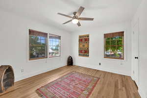 Interior space with ceiling fan, wood finished floors, baseboards, and a healthy amount of sunlight