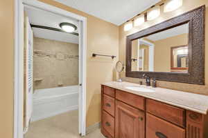 Full bathroom featuring tile patterned floors, tub / shower combination, baseboards, and vanity