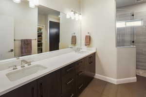 Bathroom featuring a sink, a tile shower, double vanity, and heated floors