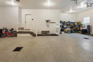Garage featuring in floor drains, epoxy floor, utility sink, and central vacuum
