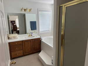 Full bathroom featuring a shower with door, a bath, and vanity