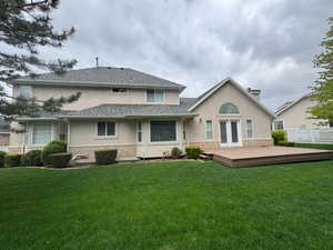 Rear view of property with a yard, stucco siding, fence, and a wooden deck