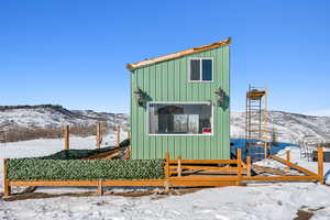 Snow covered structure featuring a mountain view and fence private yard