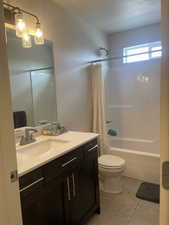 Full bathroom with vanity, toilet, shower / bathtub combination with curtain, and tile patterned floors