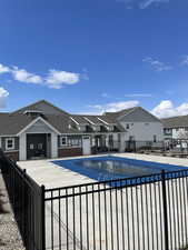 Community pool with a patio, fence, and a residential view