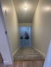 Stairway with baseboards, carpet flooring, and a textured ceiling