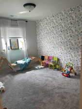 Unfurnished bedroom featuring wallpapered walls, visible vents, and carpet