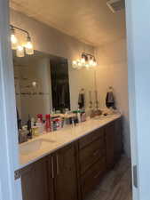 Full bath with tile patterned floors, double vanity, visible vents, and a sink