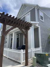 View of property exterior with a fenced front yard, a pergola, and board and batten siding