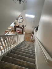 Stairs featuring a wealth of natural light, a chandelier, a towering ceiling, and wood finished floors