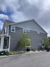 View of side of property with central air condition unit, board and batten siding, and fence
