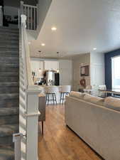 Living room with light wood-type flooring, stairway, recessed lighting, and a textured ceiling
