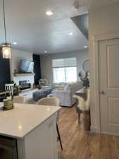 Living room featuring recessed lighting, a textured ceiling, light wood-style flooring, and a glass covered fireplace