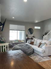 Living room with stairway, wood finished floors, and recessed lighting