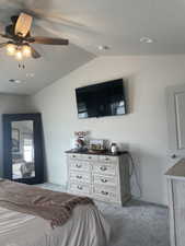 Carpeted bedroom featuring vaulted ceiling, baseboards, visible vents, and ceiling fan