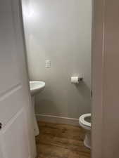 Bathroom with toilet, baseboards, and wood finished floors