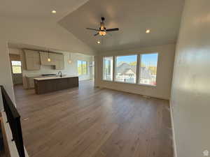 Living area featuring a healthy amount of sunlight, light wood-style flooring, ceiling fan, and high vaulted ceiling