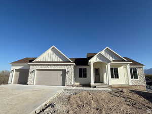 View of front of property featuring a porch, an attached garage, stone siding, driveway, and board and batten siding