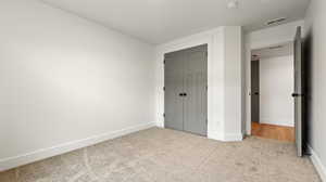 Unfurnished bedroom featuring carpet, visible vents, baseboards, and a closet