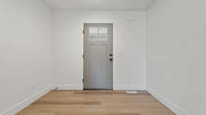 Entryway with light wood finished floors, visible vents, and baseboards