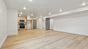 Unfurnished living room with baseboards, light wood-type flooring, and recessed lighting