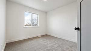 Empty room with carpet flooring, visible vents, and baseboards
