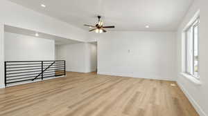 Spare room featuring baseboards, a wealth of natural light, light wood finished floors, and ceiling fan