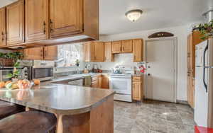 Kitchen with a sink, a peninsula, white appliances, stone finish floor, and a toaster