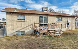 Rear view of house featuring a yard, brick siding, a deck, and fence