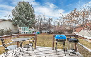 Wooden deck featuring a lawn, area for grilling, and fence
