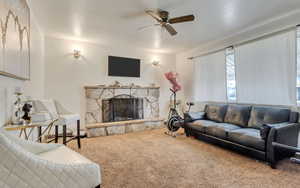 Living area with a ceiling fan, carpet flooring, and a fireplace