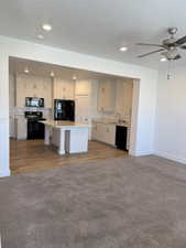 Kitchen featuring light countertops, backsplash, open floor plan, and black appliances