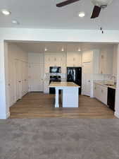 Kitchen with a sink, tasteful backsplash, black appliances, ceiling fan, and a kitchen island