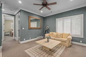 Carpeted living area featuring crown molding, a ceiling fan, visible vents, and recessed lighting