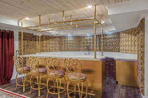 Bar with wet bar, wooden ceiling, dark wood-style flooring, and a sink