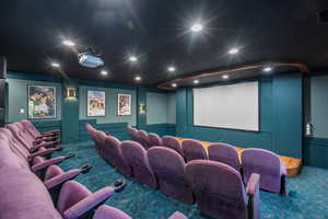 Carpeted cinema room with visible vents, a decorative wall, and recessed lighting